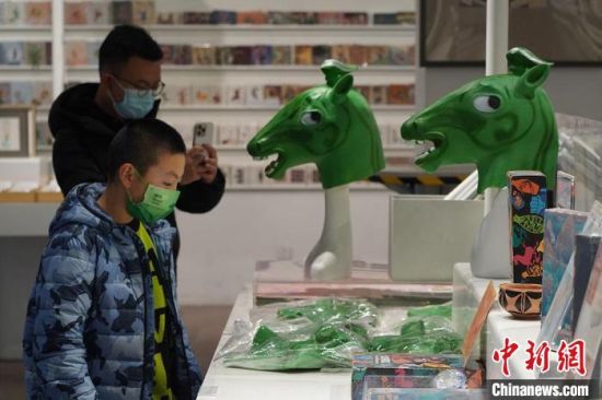 圖為“神馬來(lái)了”銅奔馬頭套吸引參觀者駐足?！【琶赖┰?攝