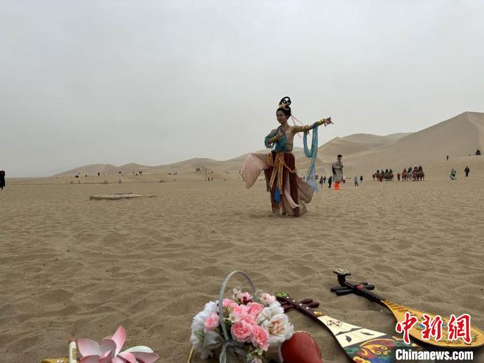 圖為2023年4月底，敦煌大漠“逐舞者”奧楠在鳴沙山月牙泉景區(qū)視頻直播敦煌舞?！●T志軍 攝