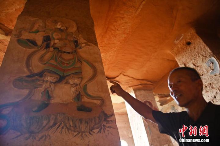 7月15日，甘肅省平?jīng)鍪袥艽h百里石窟長廊羅漢洞石窟內(nèi)，該窟文保員郭建平介紹窟內(nèi)石刻彩繪壁畫。郭建平家中三代人曾自發(fā)保護羅漢洞石窟。羅漢洞石窟遺存40余個窟龕，以北魏至清代風(fēng)格為主。中新社記者 李亞龍 攝</p>
<p>